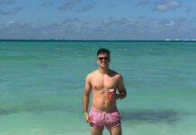 From Beach Babe to Boardroom Boss ! Shirtless Nigel de Csernatony standing in the ocean in Mexico, wearing bright pink swim trunks.